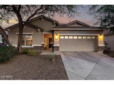 Charming home featuring a two-car garage, neutral stucco, stone accents, and a meticulously manicured landscape at 5113 W Molly Ln, Phoenix, AZ 85083