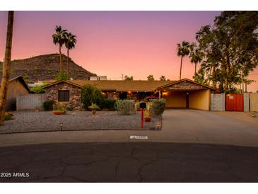 Charming stone home with lush landscaping and a covered carport provides curb appeal and convenience at 1326 W Joan De Arc Ave, Phoenix, AZ 85029