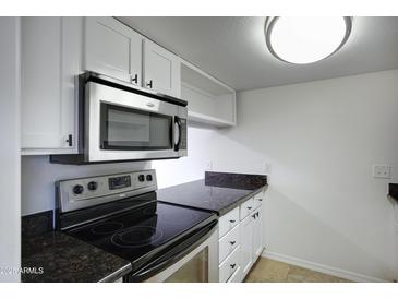Well-lit kitchen with stainless steel microwave, oven and dark granite countertops at 3619 E Monterosa St # 202, Phoenix, AZ 85018
