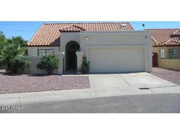 Charming single-story home featuring a stucco exterior, red tile roof, and desert landscaping at 7725 W Mcrae W Way, Glendale, AZ 85308