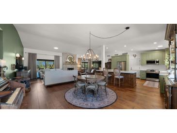 Open-concept kitchen features green cabinetry, a round dining table with hardwood floors, and stainless steel appliances at 8049 E Serene St, Carefree, AZ 85377
