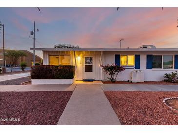 Charming single-story home with blue shutters, desert landscaping, and a welcoming entrance at dusk at 10516 W Peoria Ave, Sun City, AZ 85351