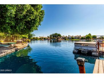 Scenic waterfront view featuring a private dock, serene lake, and lush trees with neighborhood homes in the background at 1379 E Butler Cir, Chandler, AZ 85225