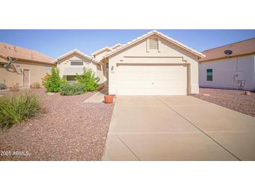 Inviting single-story home with a two-car garage, desert landscaping, and mature flowering bushes at 19961 N Coyote Lakes Pkwy, Surprise, AZ 85378
