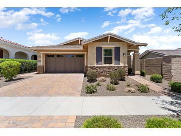 Charming single-story home with a two-car garage, brick driveway, and manicured landscaping at 20684 W Meadowbrook Ave, Buckeye, AZ 85396