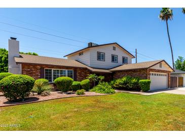 Charming two-story home featuring a well-maintained lawn, lush landscaping, and a brick facade with a two car garage at 2547 W Naranja Ave, Mesa, AZ 85202