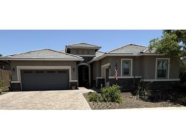 Charming single-story home with a paved driveway, gray garage door, stone accents, and well-maintained landscaping at 30287 N 115Th Dr, Peoria, AZ 85383