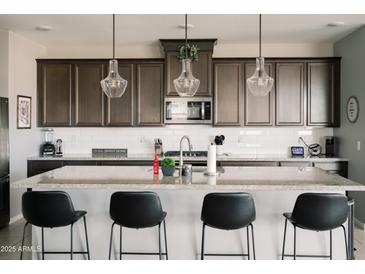 An open kitchen featuring granite countertops, stainless appliances, and modern pendant lighting at 4040 E Caitlin Dr, San Tan Valley, AZ 85140