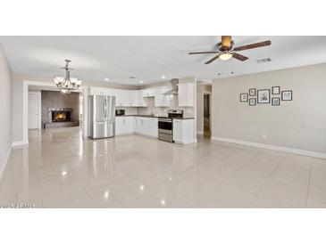 Bright, open kitchen featuring white cabinetry, stainless steel appliances, and a seamless flow to the dining area with a cozy fireplace at 4154 W Morten Ave, Phoenix, AZ 85051
