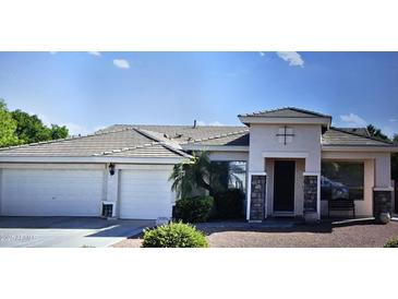 Charming single-story home featuring a three-car garage and a welcoming entrance with decorative stone accents at 4429 E Downing Cir, Mesa, AZ 85205