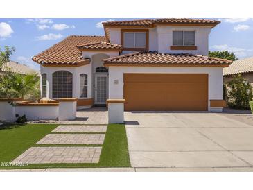 Inviting two-story home with a well-maintained yard and a two-car garage with a pathway to the front door at 5211 W Wikieup Ln, Glendale, AZ 85308
