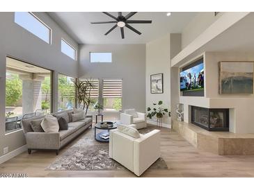 Bright living room with a fireplace, large windows, ceiling fan, and modern decor at 7128 E Bramble Berry Ln, Scottsdale, AZ 85266