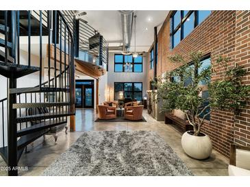 Stunning living room features exposed brick, a spiral staircase, and plenty of natural light at 914 E Osborn Rd # 404, Phoenix, AZ 85014