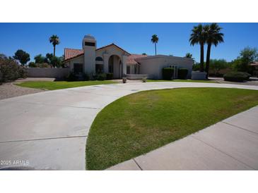 Elegant single-story home with a spacious driveway and manicured lawn at 9505 E Jenan Dr, Scottsdale, AZ 85260