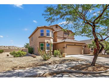 Charming two-story home with a tan facade, tiled roof, desert landscaping, and an attached two car garage at 18132 W Cardinal Dr, Goodyear, AZ 85338