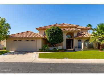 Charming two-story home featuring a tile roof, manicured lawn, and an attached three-car garage at 1834 E Willow Tree Ct, Gilbert, AZ 85234
