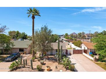 Charming home featuring desert landscaping, a tall palm tree, and a spacious driveway leading to a gated entrance at 1940 E Indianola E Ave, Phoenix, AZ 85016