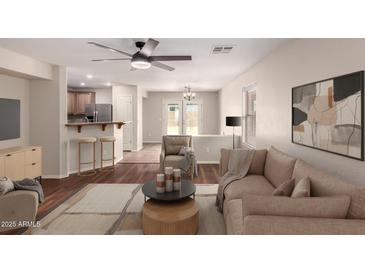 Inviting living room featuring wood floors, neutral décor, and an open layout leading to the kitchen and outdoor patio at 36538 W La Paz St, Maricopa, AZ 85138