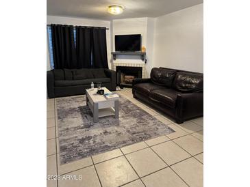 Cozy living room with a fireplace, tile floors, a coffee table and two sofas at 4601 N 102Nd Ave # 1194, Phoenix, AZ 85037