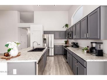 Modern kitchen featuring gray cabinets, stainless steel appliances, granite countertops, and recessed lighting at 11622 W Palm Brook Dr, Avondale, AZ 85392