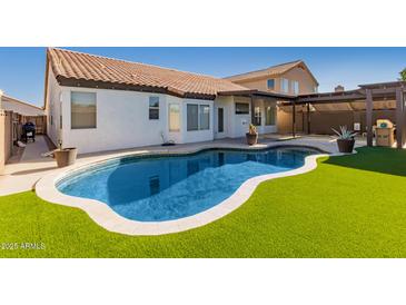 Private backyard oasis with a pool, synthetic grass and covered patio for relaxing at 11622 W Palm Brook Dr, Avondale, AZ 85392