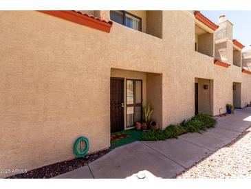 Townhouse exterior featuring a tan stucco facade, terracotta roof, and well-kept landscaping at 1401 E Puget Ave # 10, Phoenix, AZ 85020