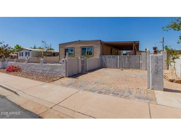 Charming single-Gathering home featuring a gated driveway, covered parking, and a well-maintained front yard at 3952 E Baywood Ave, Mesa, AZ 85206
