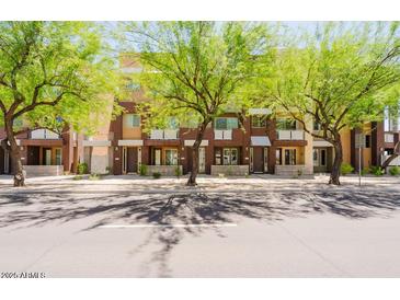 Street view of modern townhomes with well-maintained landscaping and trees along the sidewalk at 6605 N 93Rd Ave # 1035, Glendale, AZ 85305