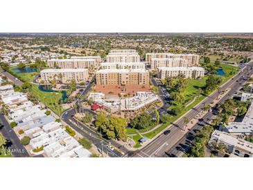 An aerial view of a condo complex surrounded by lush landscaping, mature trees, and a neighboring street at 7910 E Camelback Rd # 302, Scottsdale, AZ 85251