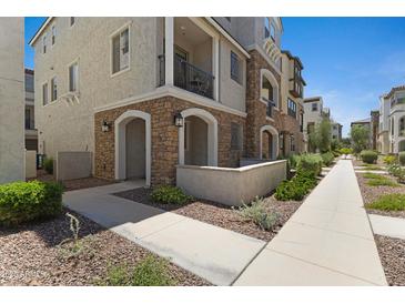 Stunning exterior of a multi-story home with stone accents and a private balcony, beautifully landscaped with a sidewalk at 1694 E Dogwood Ln, Gilbert, AZ 85295