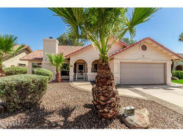 Charming single-story home with well-maintained landscaping, desert rock, mature palm trees, and a tile roof at 7139 W Mcrae Way, Glendale, AZ 85308