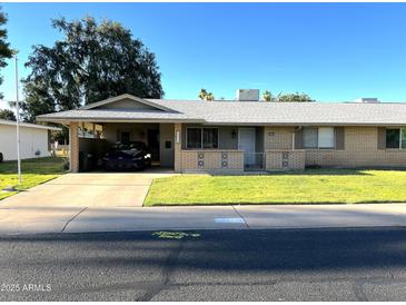 Charming single-story home featuring a carport, brick accents, and a well-maintained front lawn at 10726 W Kelso Dr, Sun City, AZ 85351