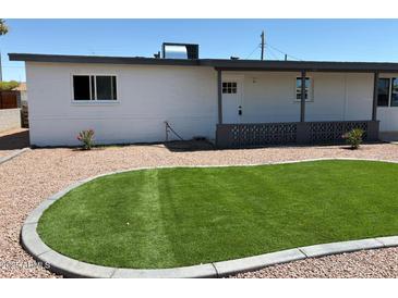 Well-maintained home featuring desert landscaping, a small lawn, and a charming covered porch at 2023 W Wayland Rd, Phoenix, AZ 85041
