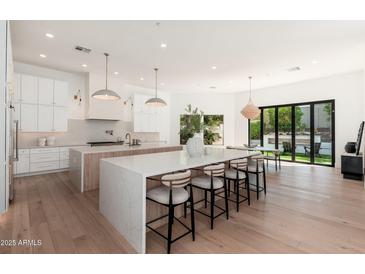 Bright, open kitchen featuring a large island, white cabinets, and modern lighting fixtures at 7710 E Tardes Dr, Scottsdale, AZ 85255