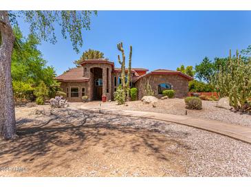 Stunning stone home with a beautiful arched entryway and desert landscaping with mature Saguaro cacti at 8606 S Dorsey Ln, Tempe, AZ 85284