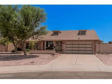 Charming single-story home featuring a brick facade, well-maintained landscaping, and a two-car garage at 8803 N 105Th Dr, Peoria, AZ 85345