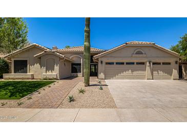 Charming single-story home featuring desert landscaping, a three car garage, and a tile roof at 9112 E Palm Tree Dr, Scottsdale, AZ 85255