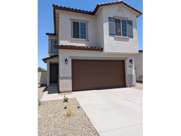 Charming two-story home featuring a brown two-car garage, desert landscaping, and shutters at 9412 E Sequence Ave, Mesa, AZ 85212