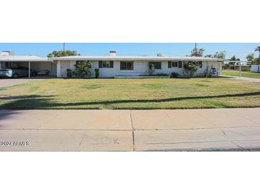 Charming single story home with a well-maintained lawn, mature trees, and covered parking at 10307 W Oakmont Dr, Sun City, AZ 85351