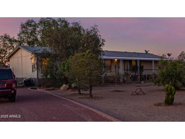 Home exterior featuring desert landscaping with mature plants, covered front porch, and gravel yard at 22216 W Bajada Dr, Wittmann, AZ 85361