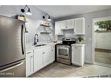 Bright kitchen features white cabinets, stainless steel appliances, and modern fixtures at 3646 N 67Th Ave # 64, Phoenix, AZ 85033
