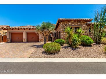 Charming stone home featuring a two-car garage, desert landscaping, and a brick driveway at 4041 N Silver Ridge Cir, Mesa, AZ 85207