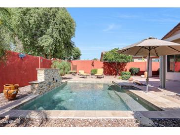 Sparkling pool featuring a stone water feature and umbrella shaded lounge area at 10786 W Chisholm Dr, Sun City, AZ 85373