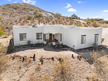Charming white home with desert landscaping and mountain backdrop, creating a serene Southwestern setting at 1550 W Adobe Dam Dr, San Tan Valley, AZ 85144