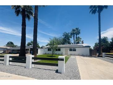 Charming home with solar panels and a beautifully landscaped front yard with palm trees at 2201 N 29Th Pl, Phoenix, AZ 85008