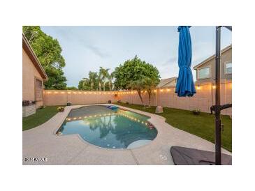 Backyard pool area featuring a lovely pool, a seating area, and well-maintained artificial turf at 7027 W Blackhawk Dr, Glendale, AZ 85308
