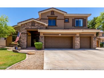 Two-story home with a three-car garage, stone accents, manicured lawn, and covered entryway at 723 E Gemini Pl, Chandler, AZ 85249