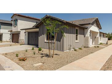 Charming home features low maintenance desert landscaping and a gray two-car garage at 9416 E Sequence Ave, Mesa, AZ 85212