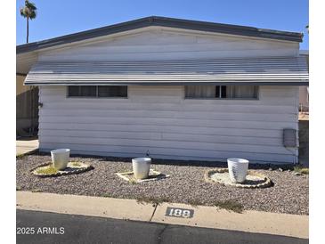 Charming single-story home with a grey trim, three white decorative flowerpots, and well-kept landscaping at 11411 N 91St Ave # 188, Peoria, AZ 85345