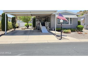 Charming home featuring a covered carport, wheelchair ramp, and manicured landscaping with American flag at 2233 E Behrend Dr # 121, Phoenix, AZ 85024